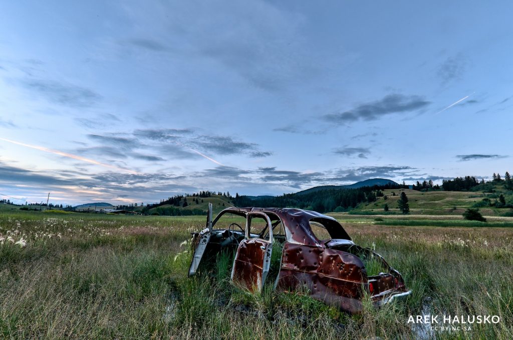 Kamloops Cold Creek Road abandoned car in grass field during sunset.